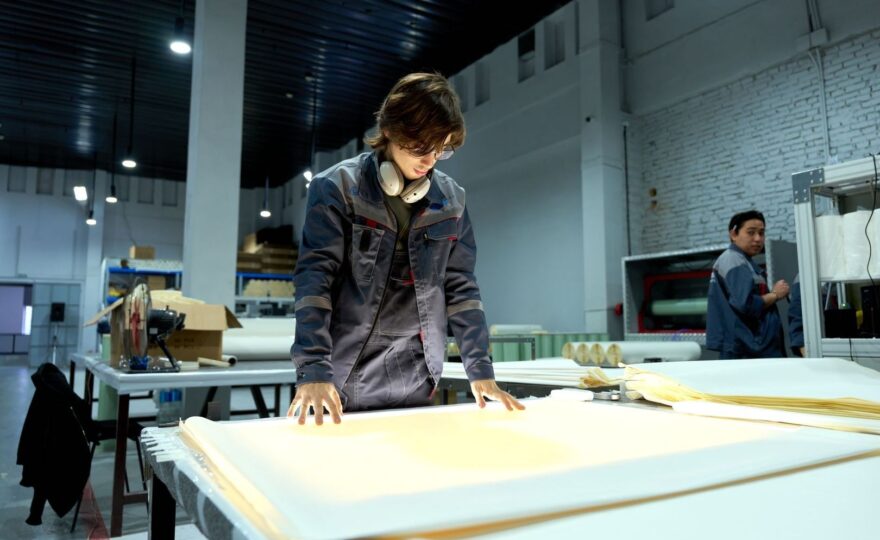 Workers inspect large sheets of material in a manufacturing facility