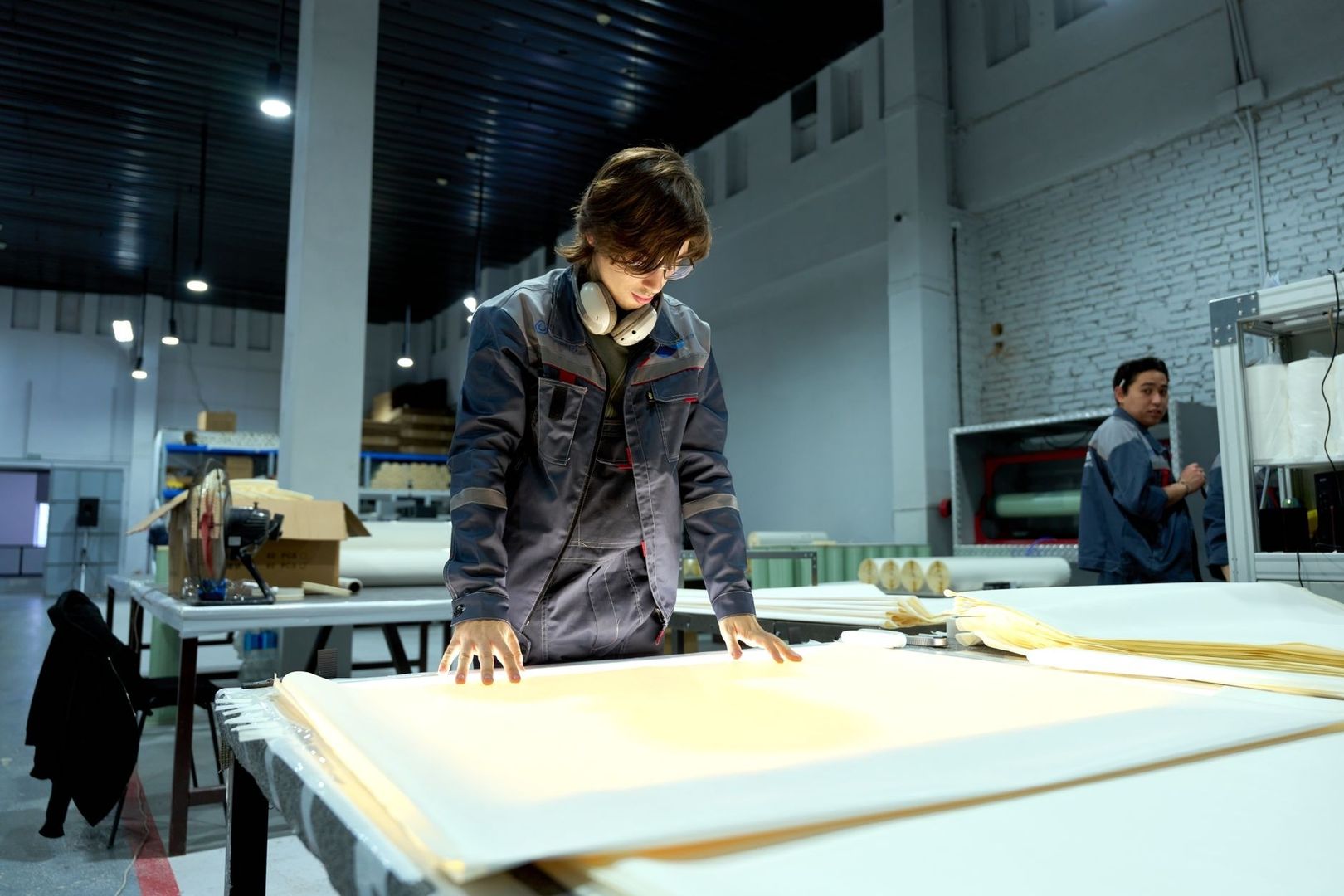 Workers inspect large sheets of material in a manufacturing facility