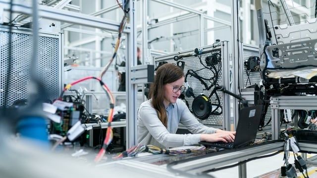 Engineer using a laptop beside complex automotive testing equipment